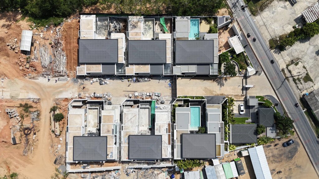 Top-down construction photograph of villa roofs and pools