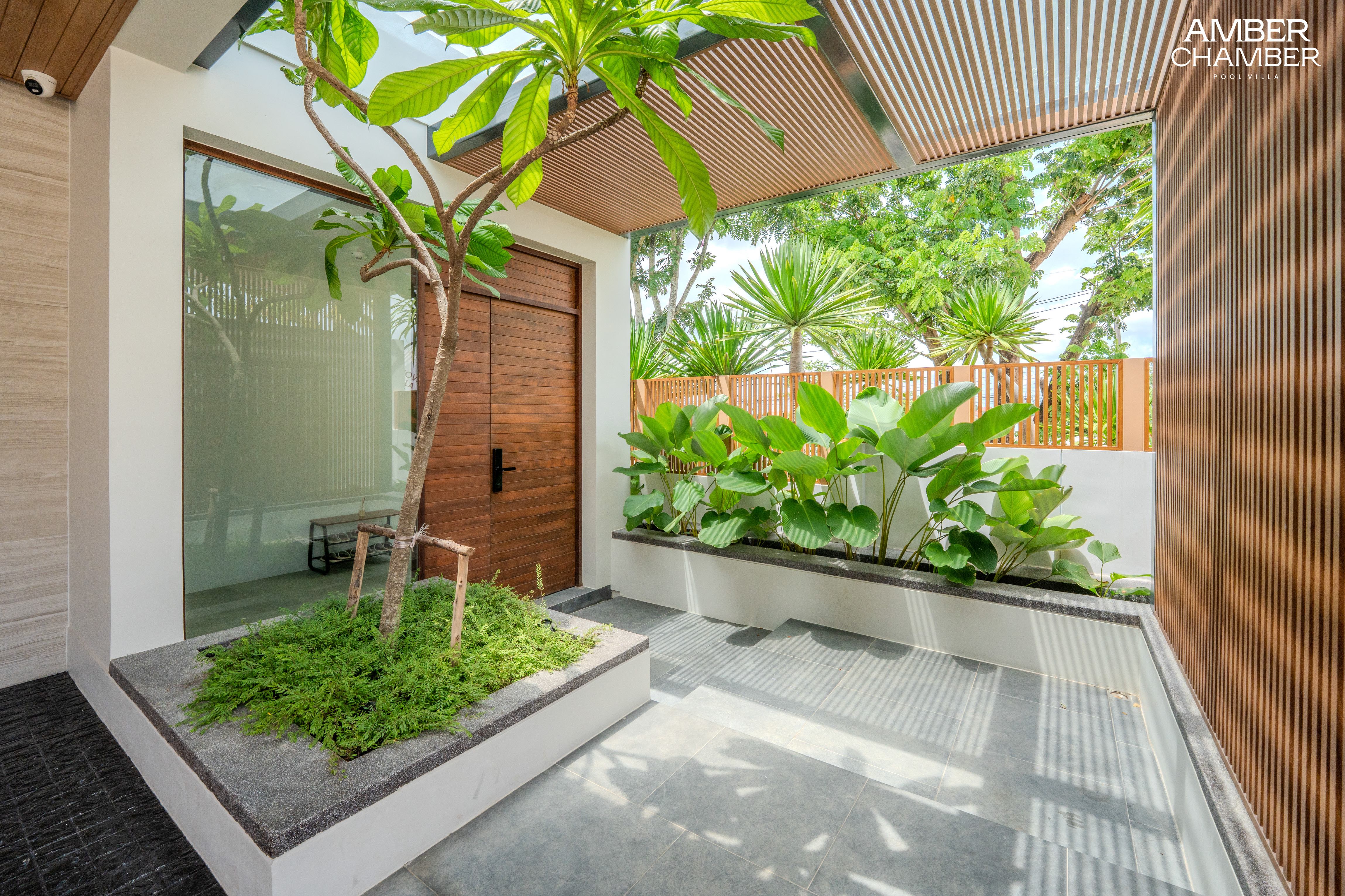 Private entrance courtyard with tropical planting and timber door